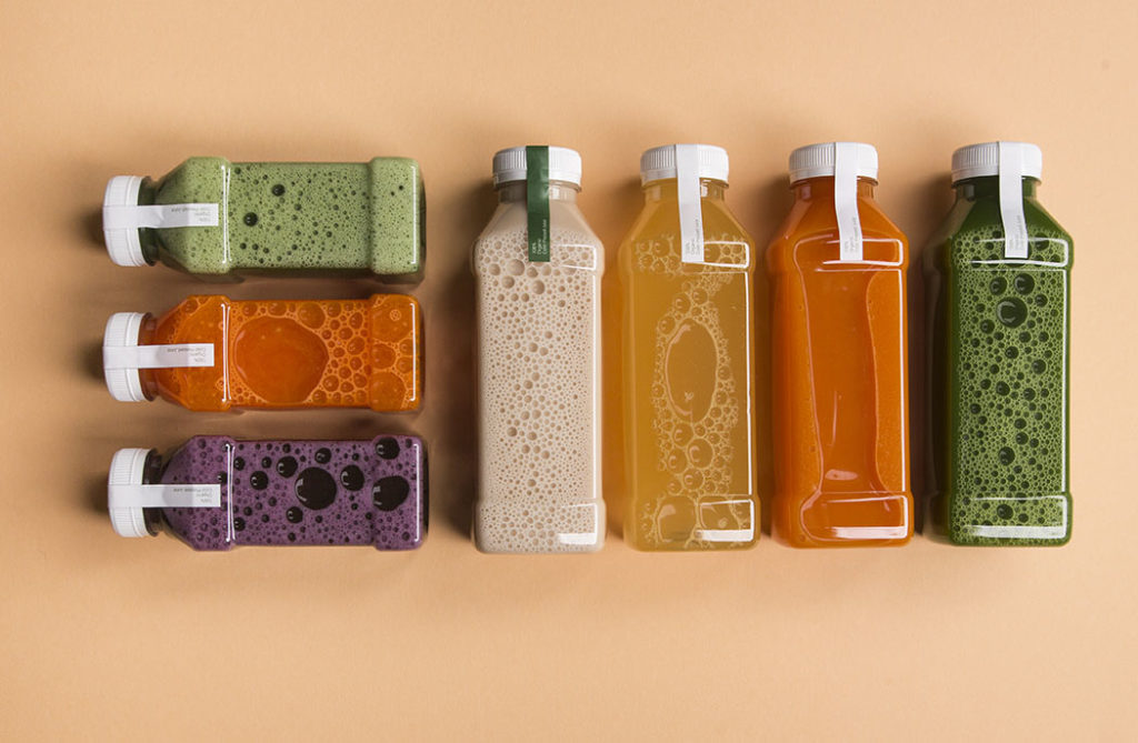 Assorted colorful bottled juices on beige background.