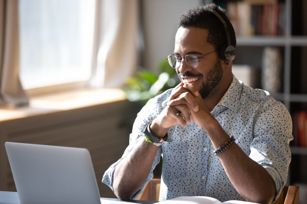 Man smiling with headphones at laptop indoors