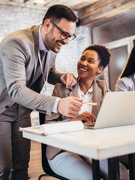 Business colleagues collaborating at a laptop in office.